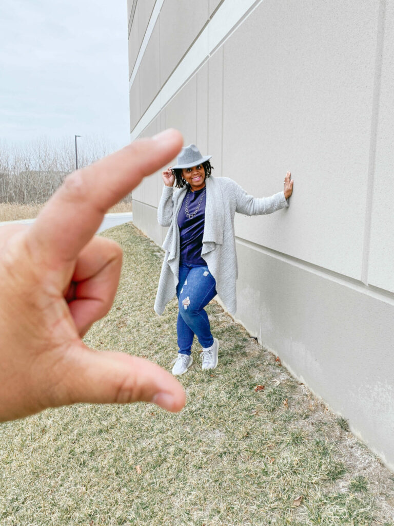 girl standing against wall, seeming to be squeezed between fingers